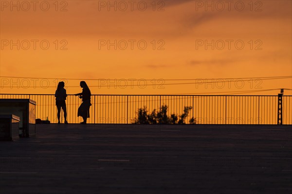 Two woman on the terrace of the Dresden Congress Centre in front of the summer evening sky