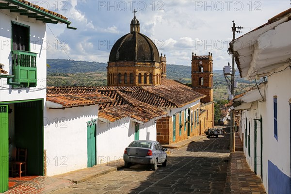 View to a street with typical traditional houses and cathedral in historic town Barichara on a sunny day, Colombia, South America