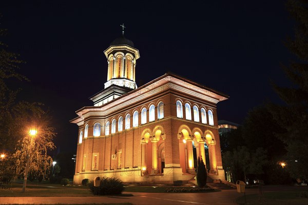 Illuminated church at night with a high tower, blue sky and visible windows. Craiova, Krajowa, Kragau, Church of St Treime, Holy Trinity Church, Bisceria Sfanta Treime, Small Wallachia, Romania, Europe