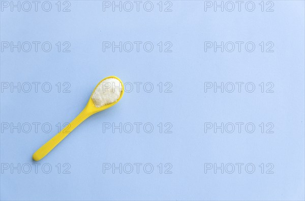 Spoon with sugar close-up on a light blue background