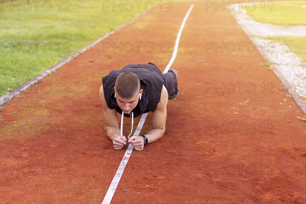 Young man doing plank exercise in the morning outdoor on the running race track