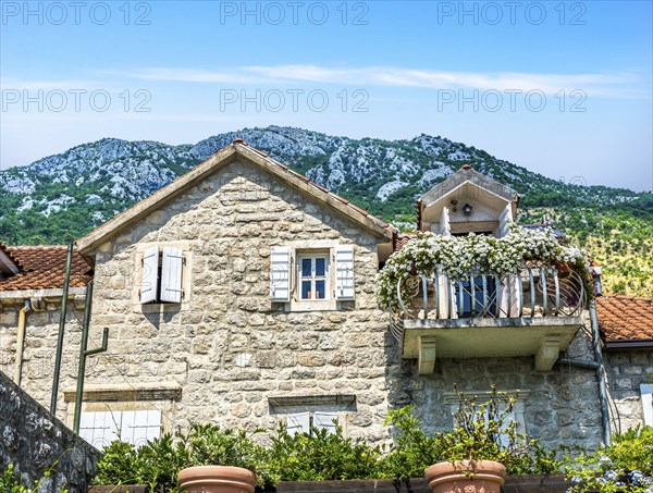 Old house with flowers on balcony in Perast, Montenegro, Europe