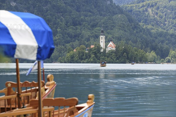 Lake Bled with traditional boat. Beautiful mountain lake in summer with small Church on island with castle on cliff and alps in the background