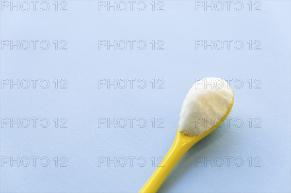 Spoon with sugar close-up on a light blue background