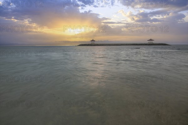 Beautiful seascape in the morning. Tropical sandy beach with breakwater and reflection of the sky in the calm water. Morning landscape, taken in Sanur, Bali, Indonesia, Asia