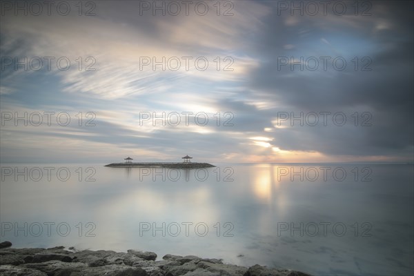 Beautiful seascape in the morning. Tropical sandy beach with breakwater and reflection of the sky in the calm water. Morning landscape, taken in Sanur, Bali, Indonesia, Asia