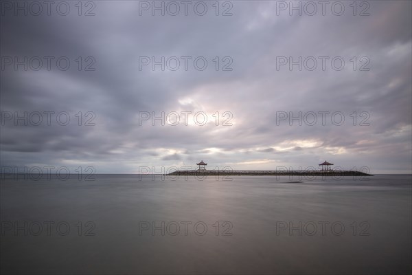 Beautiful seascape in the morning. Tropical sandy beach with breakwater and reflection of the sky in the calm water. Morning landscape, taken in Sanur, Bali, Indonesia, Asia