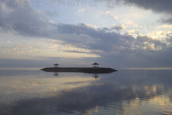 Beautiful seascape in the morning. Tropical sandy beach with breakwater and reflection of the sky in the calm water. Morning landscape, taken in Sanur, Bali, Indonesia, Asia