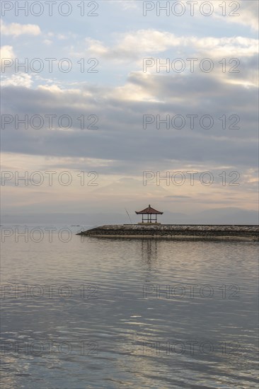 Beautiful seascape in the morning. Tropical sandy beach with breakwater and reflection of the sky in the calm water. Morning landscape, taken in Sanur, Bali, Indonesia, Asia