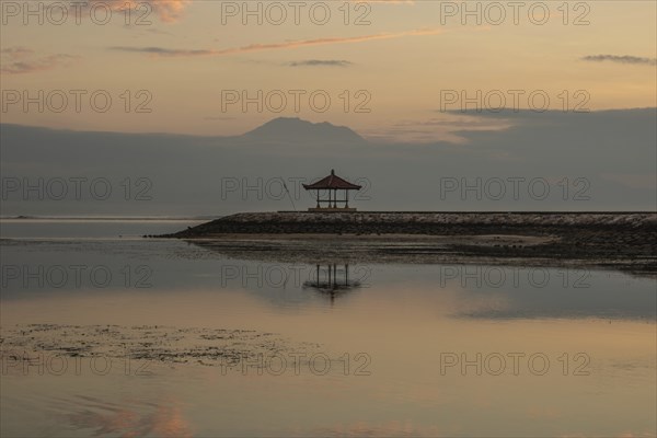 Beautiful seascape in the morning. Tropical sandy beach with breakwater and reflection of the sky in the calm water. Morning landscape, taken in Sanur, Bali, Indonesia, Asia