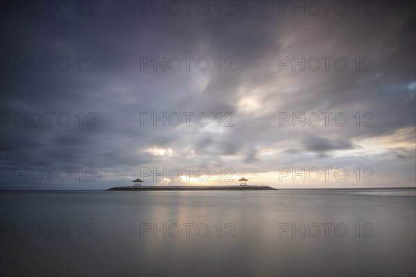 Beautiful seascape in the morning. Tropical sandy beach with breakwater and reflection of the sky in the calm water. Morning landscape, taken in Sanur, Bali, Indonesia, Asia