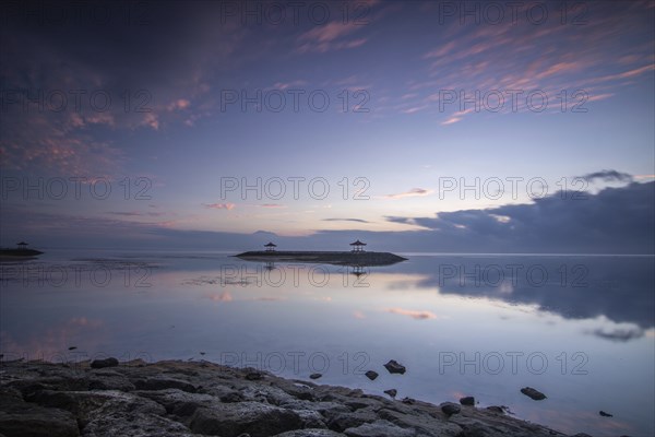Beautiful seascape in the morning. Tropical sandy beach with breakwater and reflection of the sky in the calm water. Morning landscape, taken in Sanur, Bali, Indonesia, Asia