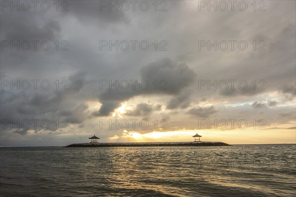 Beautiful seascape in the morning. Tropical sandy beach with breakwater and reflection of the sky in the calm water. Morning landscape, taken in Sanur, Bali, Indonesia, Asia