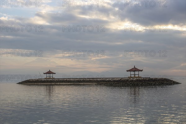 Beautiful seascape in the morning. Tropical sandy beach with breakwater and reflection of the sky in the calm water. Morning landscape, taken in Sanur, Bali, Indonesia, Asia