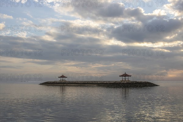 Beautiful seascape in the morning. Tropical sandy beach with breakwater and reflection of the sky in the calm water. Morning landscape, taken in Sanur, Bali, Indonesia, Asia
