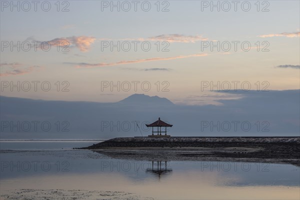 Beautiful seascape in the morning. Tropical sandy beach with breakwater and reflection of the sky in the calm water. Morning landscape, taken in Sanur, Bali, Indonesia, Asia