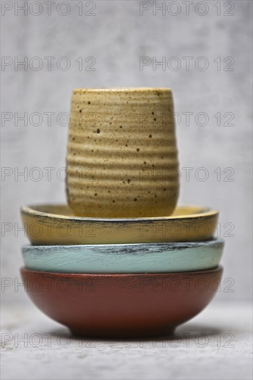 A close up photo of multi colored bowls and a homemade cup stacked together