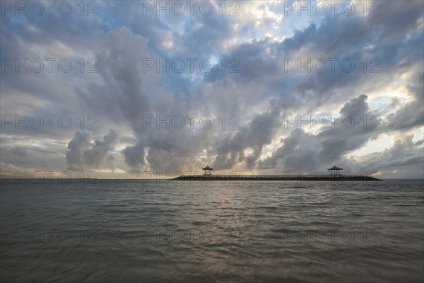 Beautiful seascape in the morning. Tropical sandy beach with breakwater and reflection of the sky in the calm water. Morning landscape, taken in Sanur, Bali, Indonesia, Asia