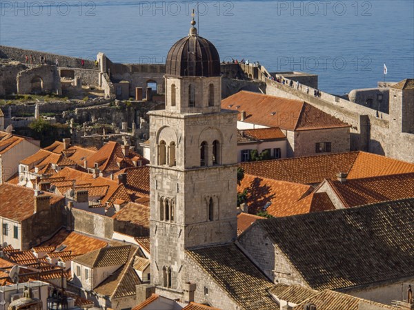 A church tower rises above a town with red roofs and a view of the sea, Dubrovnik, Mediterranean, Croatia, Europe