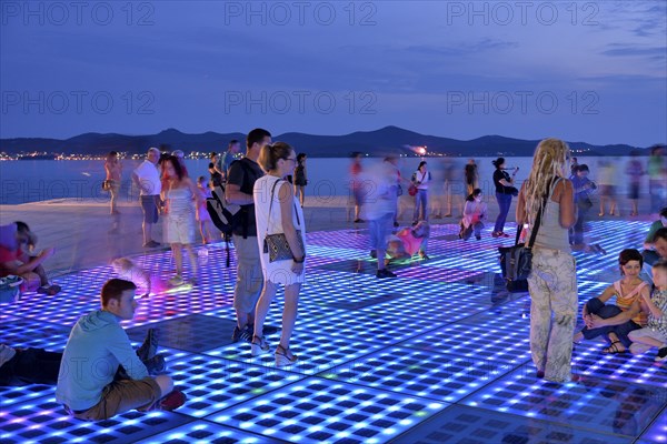 People at the Monument to the Sun, Pozdrav Suncu, by architect Nikole Bašica, at dusk, Zadar, Dalmatia, Croatia, Europe