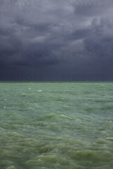 Dark rain clouds over emerald coloured sea water