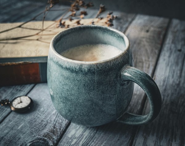 A large coffee cup standing in front of an old book