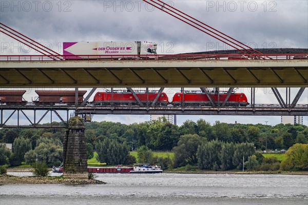 The Beeckerwerth Rhine bridge of the A42 motorway, truck traffic, in front of it the Haus-Knipp railway bridge, goods train, cargo ship on the Rhine near Duisburg, North Rhine-Westphalia, Germany, Europe