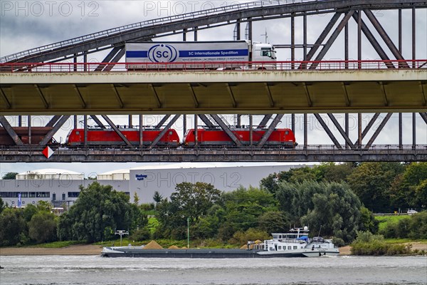 The Beeckerwerth Rhine bridge of the A42 motorway, truck traffic, in front of it the Haus-Knipp railway bridge, goods train, cargo ship on the Rhine near Duisburg, North Rhine-Westphalia, Germany, Europe