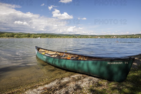 Green canoe on the shore of a lake with clear water and cloudy sky, quiet peaceful surroundings, Markelfingen, Markelfingerwinkel, Untersee, Lake Constance, Kreis Konstanz, Baden-Württemberg, Germany, Europe