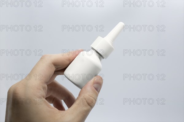 Young man is sick using nasal spray for blocked nose, spraying nose drops, hand holding nasal spray