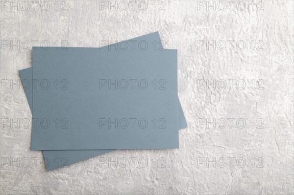 Blue paper business card, mockup on gray concrete background. Blank, flat lay, top view, still life, copy space