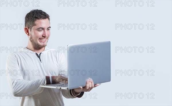 Excited guy holding and looking at an promotion on laptop screen. Portrait of happy young man standing using laptop isolated