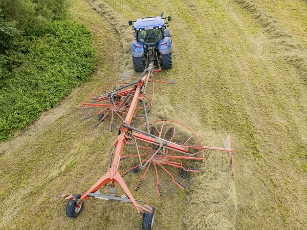 Aerial view of a tractor with hay machine in a field, surrounded by cut grass and hay bales, Dachtel. Black Forest, Germany, Europe
