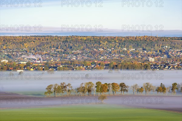 Aerial view of a small town at the foot of a mountain in a rural landscape with morning fog and autumn colours, Falköping, Sweden, Europe