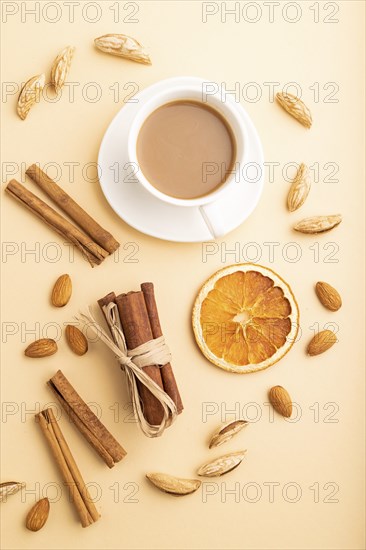 Composition with almonds, cinnamon and cup of coffee on orange pastel background. Blank, flat lay, top view, still life, close up