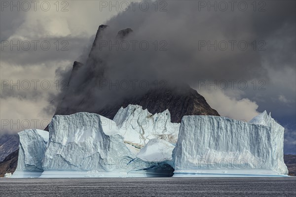 Large icebergs in fjord in front of steep mountains, cloudy mood, summer, Scoresby Sound, East Greenland, Greenland, North America