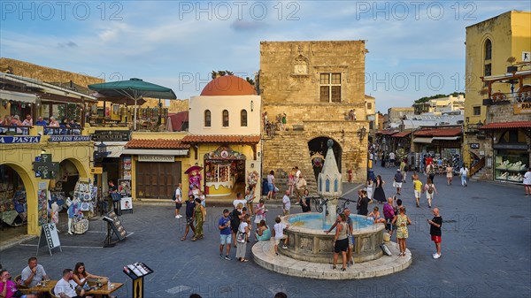 Hippocrates Square, Owl Fountain, Lively historic square with a central fountain, surrounded by medieval architecture and many tourists on a sunny day, Rhodes Old Town, Rhodes Town, Rhodes, Dodecanese, Greek Islands, Greece, Europe