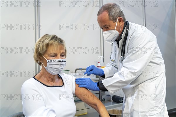 Vaccinator administers a vaccination, during the test run in the vaccination centre for corona vaccinations, in a hall at Messe Essen, by the city, the fire brigade and various aid organisations, 12 vaccination lines for a daily vaccination of up to 2400 people, operated by the North Rhine-Westphalia Association of Statutory Health Insurance Physicians