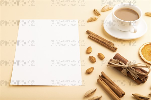 Composition with white paper sheet, almonds, cinnamon and cup of coffee. mockup on orange background. Blank, side view, still life, copy space