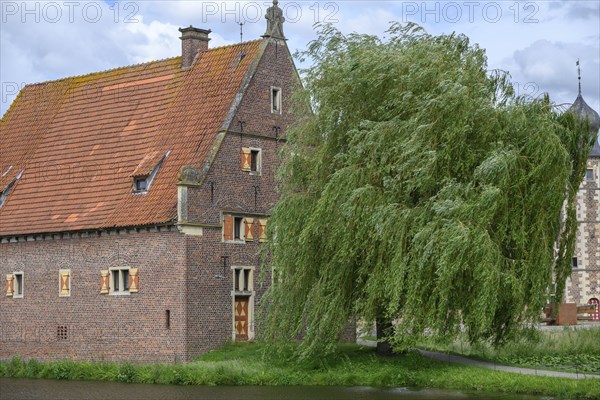 Small half-timbered building with red tiled roof by a moat, surrounded by green trees, Raesfeld, North Rhine-Westphalia, Germany, Europe
