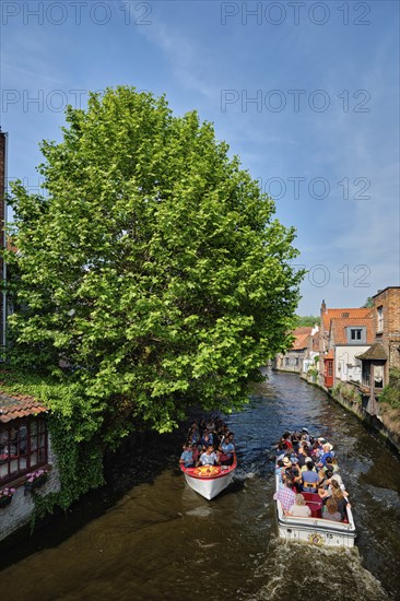 BRUGES, BELGIUM, MAY 28, 2018: Tourist boats with tourists in canal between old houses. Brugge Bruges, Belgium, Europe