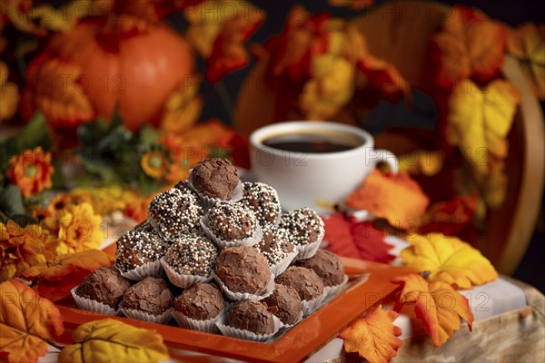 Autumnally decorated table with rum balls, colourful leaves and a cup of coffee in a cosy atmosphere