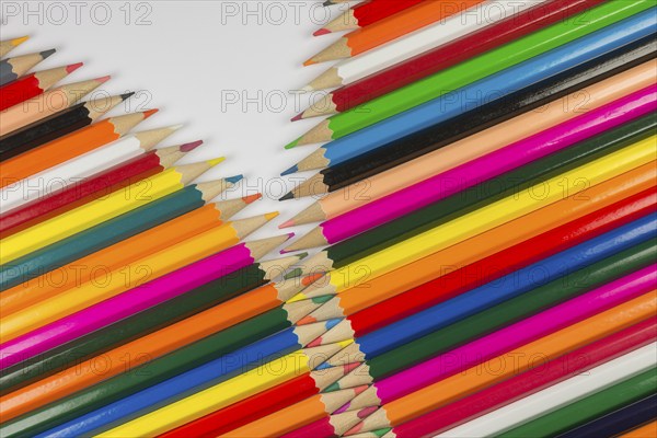 Abstract composition of a set cedar wooden colour pencils against a white background in zipper style