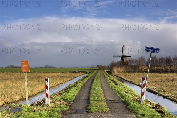 Cycle path in the nature area Donkse Laagten near Streefkerk in the Dutch region Alblasserwaard. The windmill Broekolen can be seen in the background