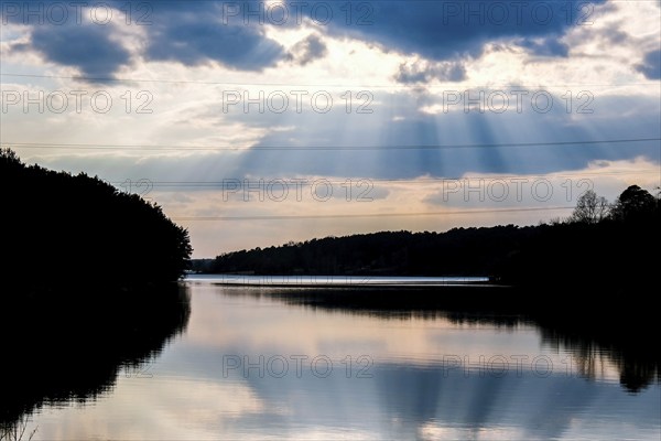 Scenic View Of Calm Lake At Sunset. River weather sun rays. Clouds. Mirror effect. Nature background