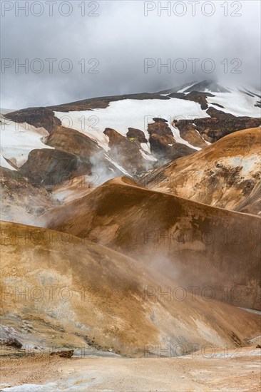 Hot springs and steaming stream between colourful rhyolite mountains with snowfields, Hveradalir geothermal area, Kerlingarfjöll, Icelandic highlands, Iceland, Europe