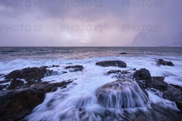 Beach of Norwegian sea on rocky coast in fjord on sunset in winter. Vareid beach, Lofoten islands, Norway, Europe