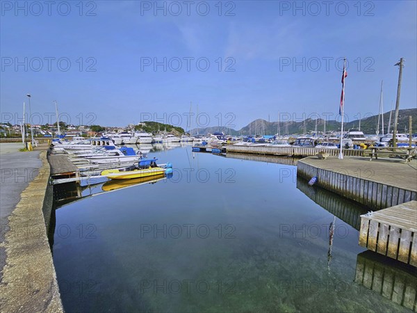 A quiet harbour with boats on a jetty, surrounded by mountains under a blue sky, Sandnes, Fylke Rogaland, Norway, Europe