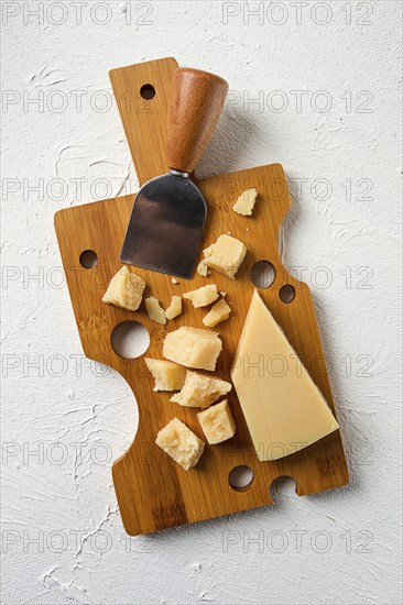 Hard cheese, parmesan, on a cutting board, cheese knife, grater, top view, no people