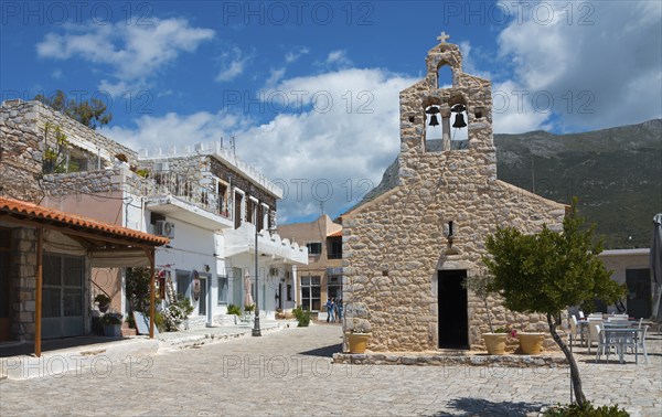 Village square with traditional stone church and white buildings under a cloudy blue sky, Church of St Athanasios, Areopoli, Areopolis, Tsimova, Itylo, Anatoliki Mani, Mani, Laconia, Peloponnese, Greece, Europe